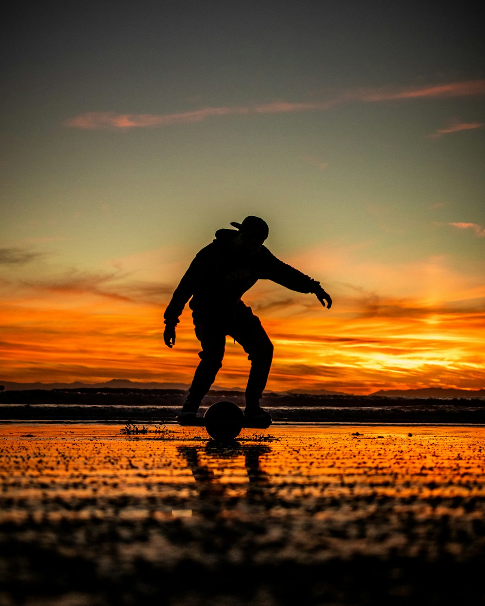 a man riding a skateboard on top of a wet beach