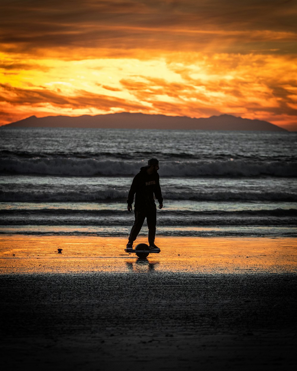 a man riding a skateboard on top of a beach