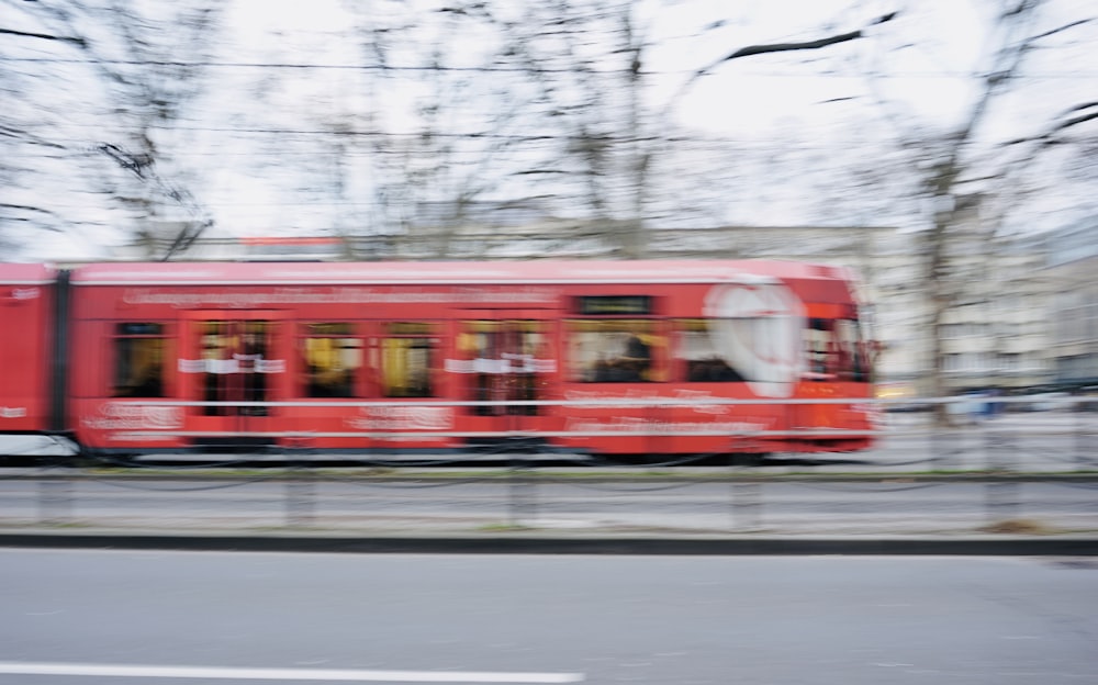 a red train traveling down train tracks next to a forest