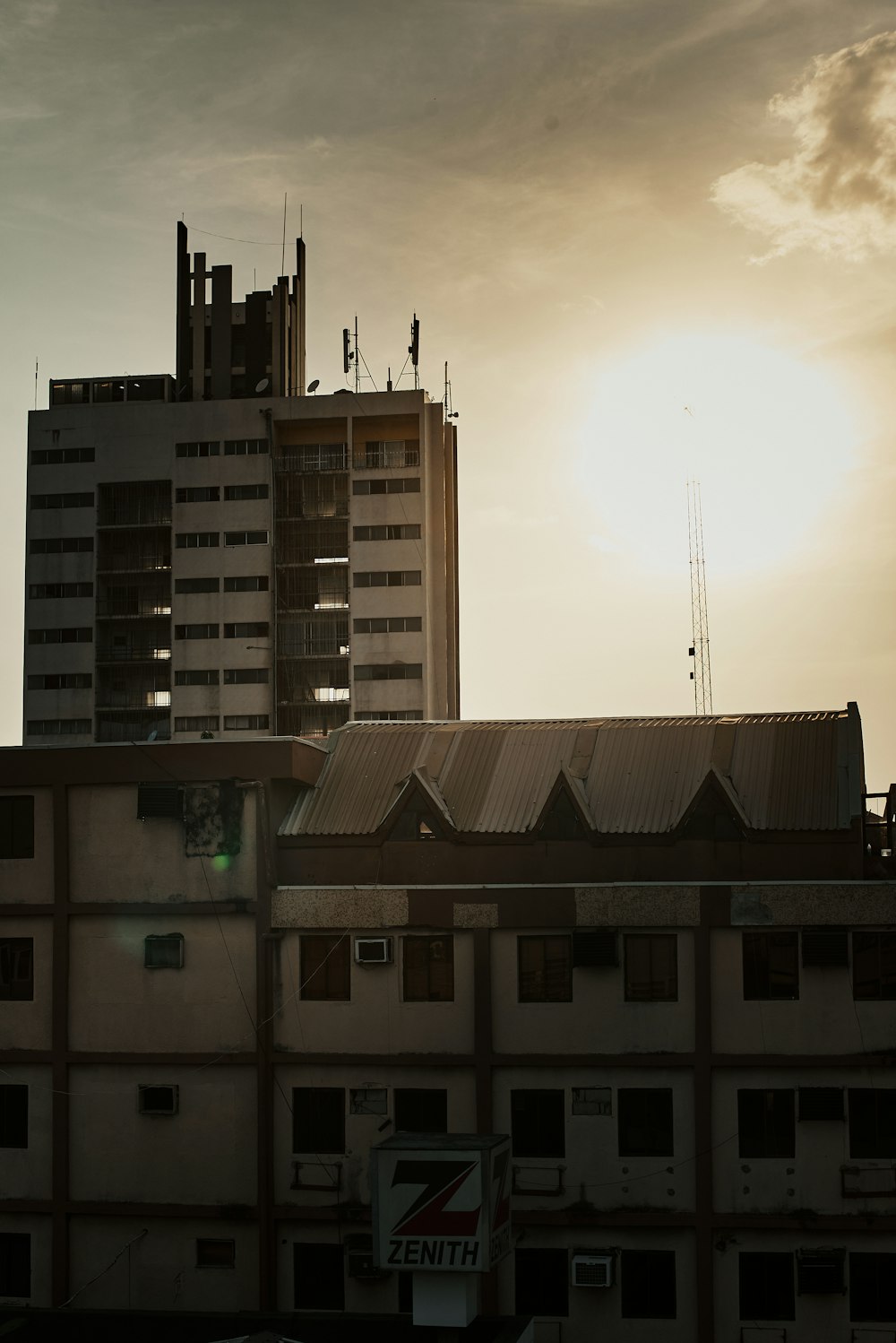 the sun is setting behind a tall building