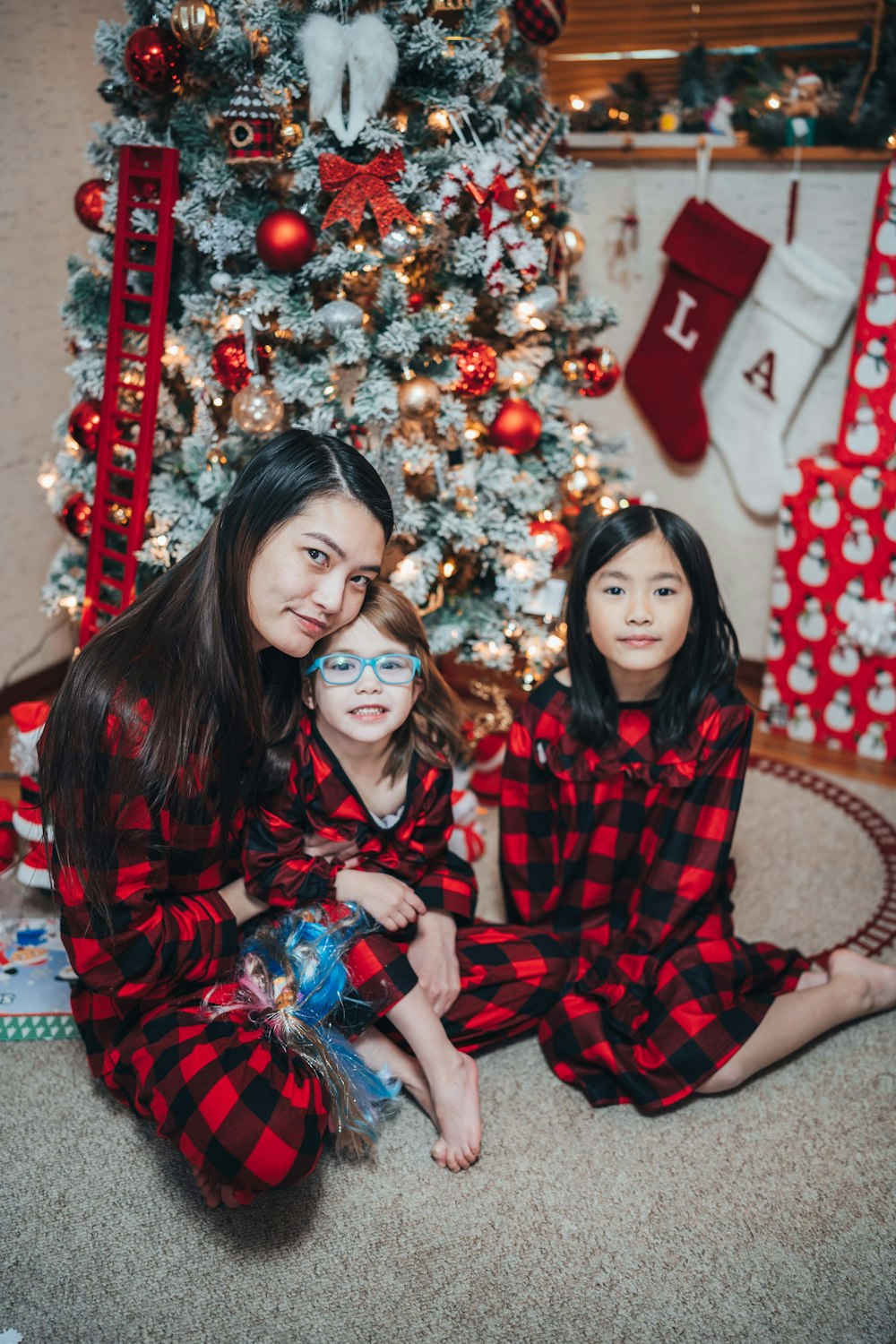 two young girls sitting in front of a christmas tree