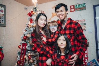 a family poses for a picture in front of a christmas tree