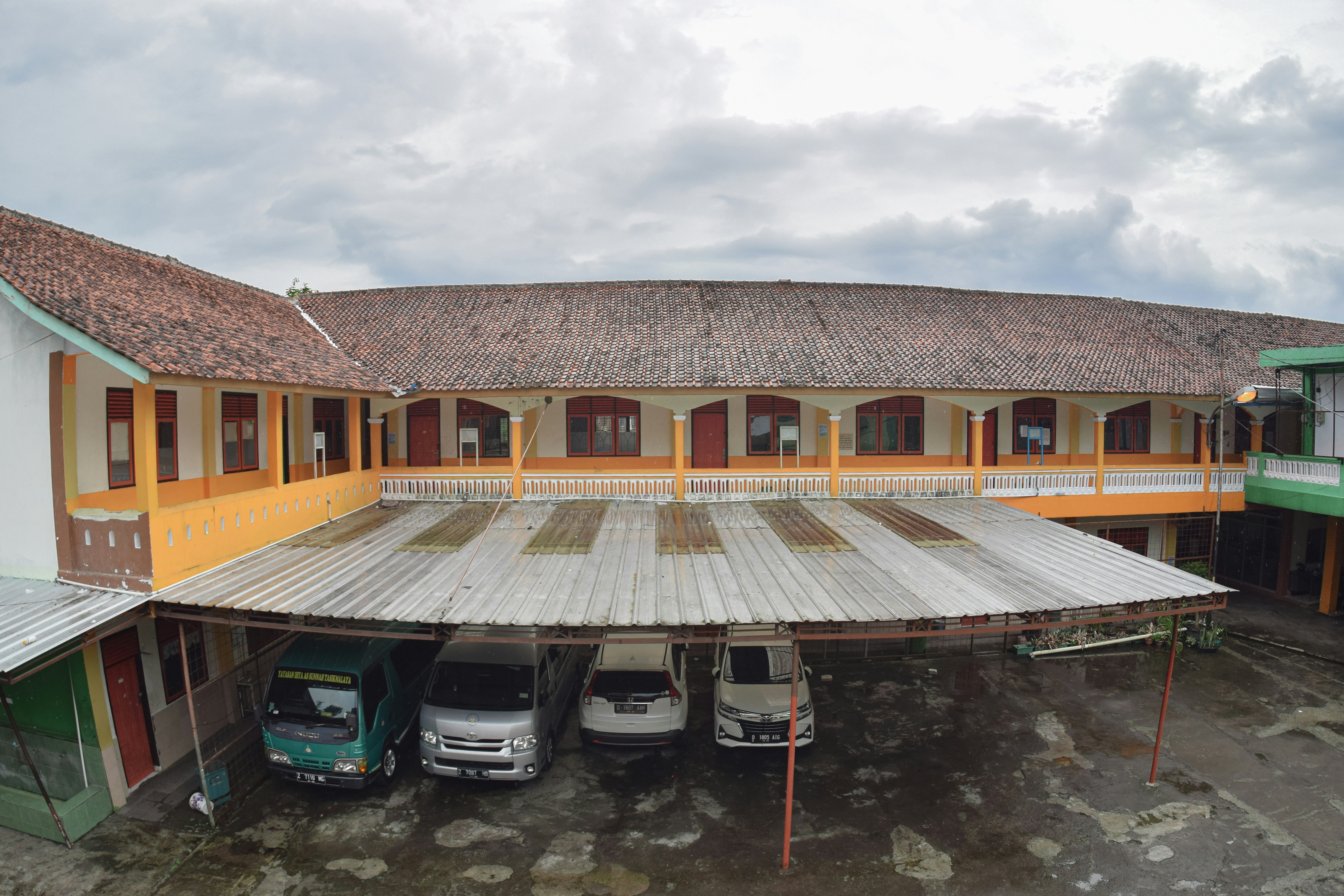Tiga mobil diparkir di tempat parkir di depan sebuah gedung