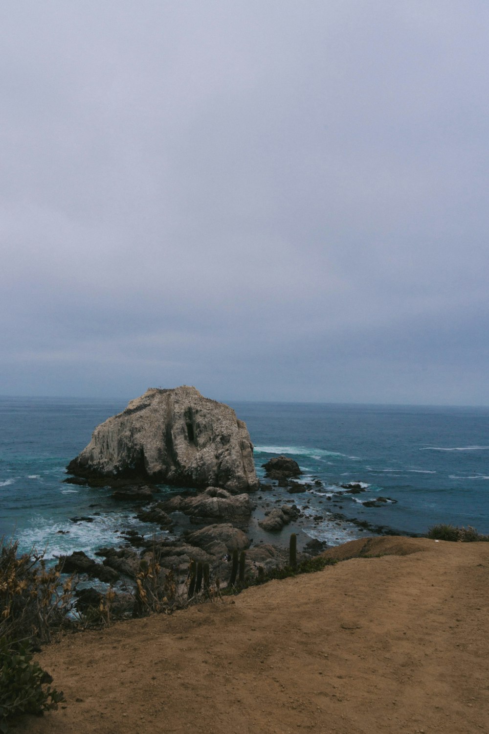 a large rock sitting on top of a beach next to the ocean