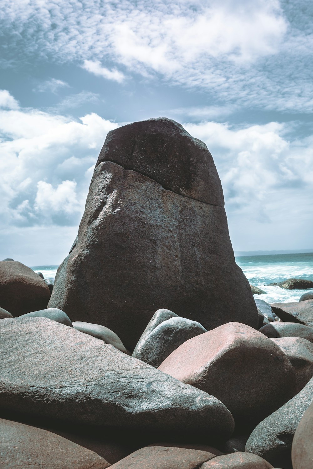 海の隣のビーチの上に座っている大きな岩