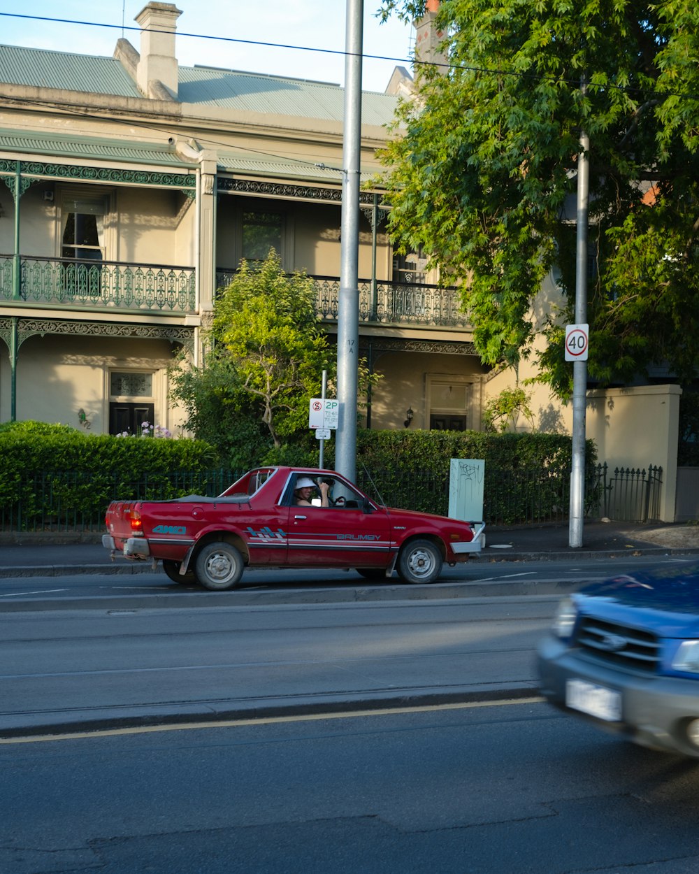 a red car driving down a street next to a tall building