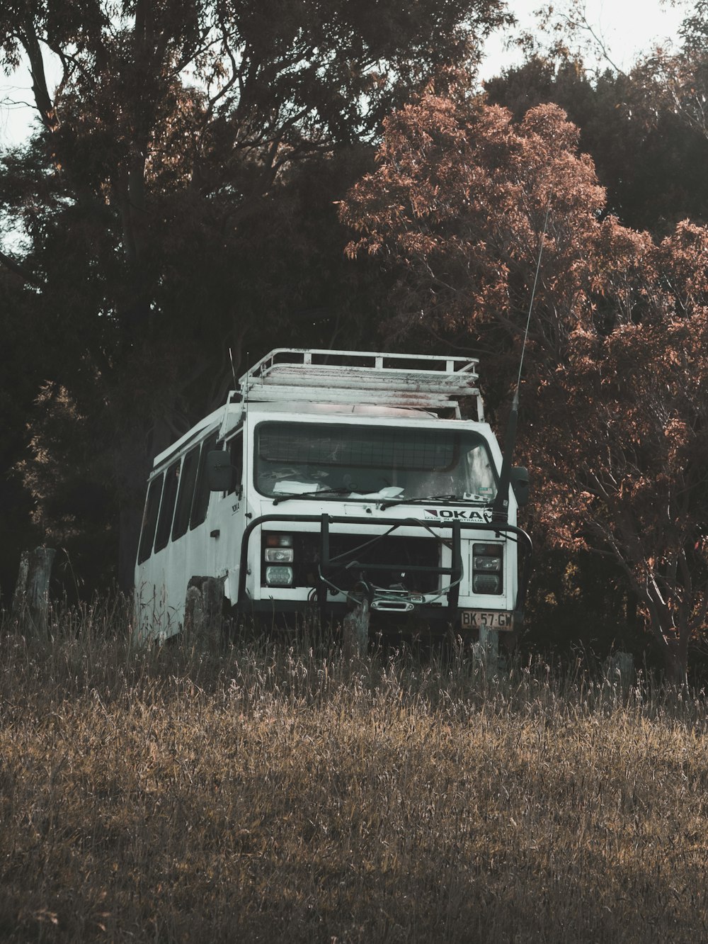 an old bus sitting in a field with trees in the background