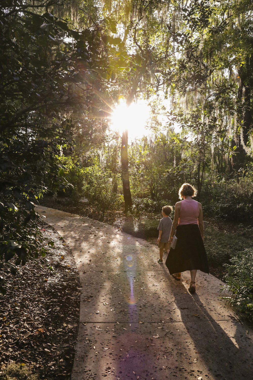 a woman and child walking down a path in the woods