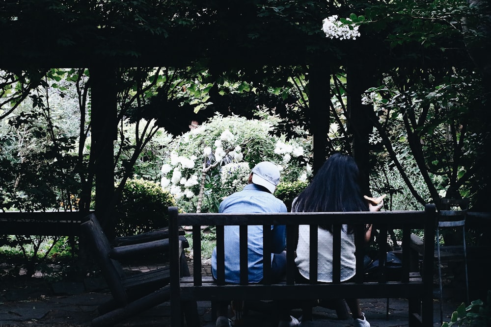 two people sitting on a bench in a park