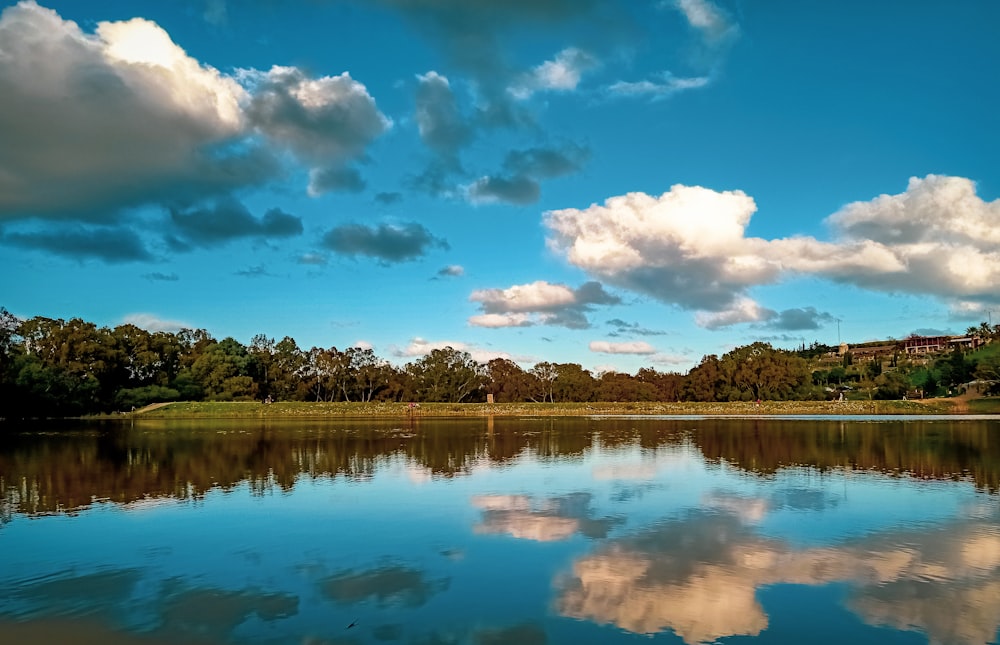 a body of water surrounded by trees and clouds