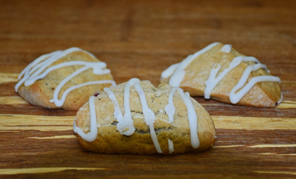three cookies with white icing on a wooden surface