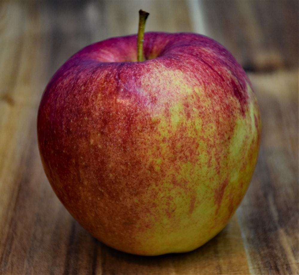나무 테이블 위에 앉아 있는 빨간 사과