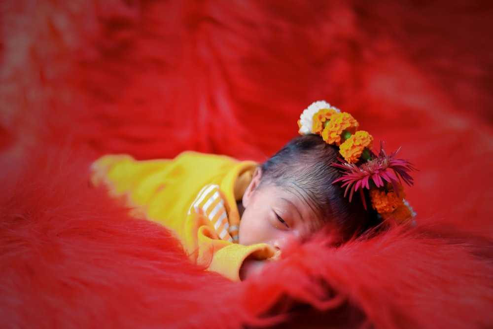 a small child is sleeping on a red blanket