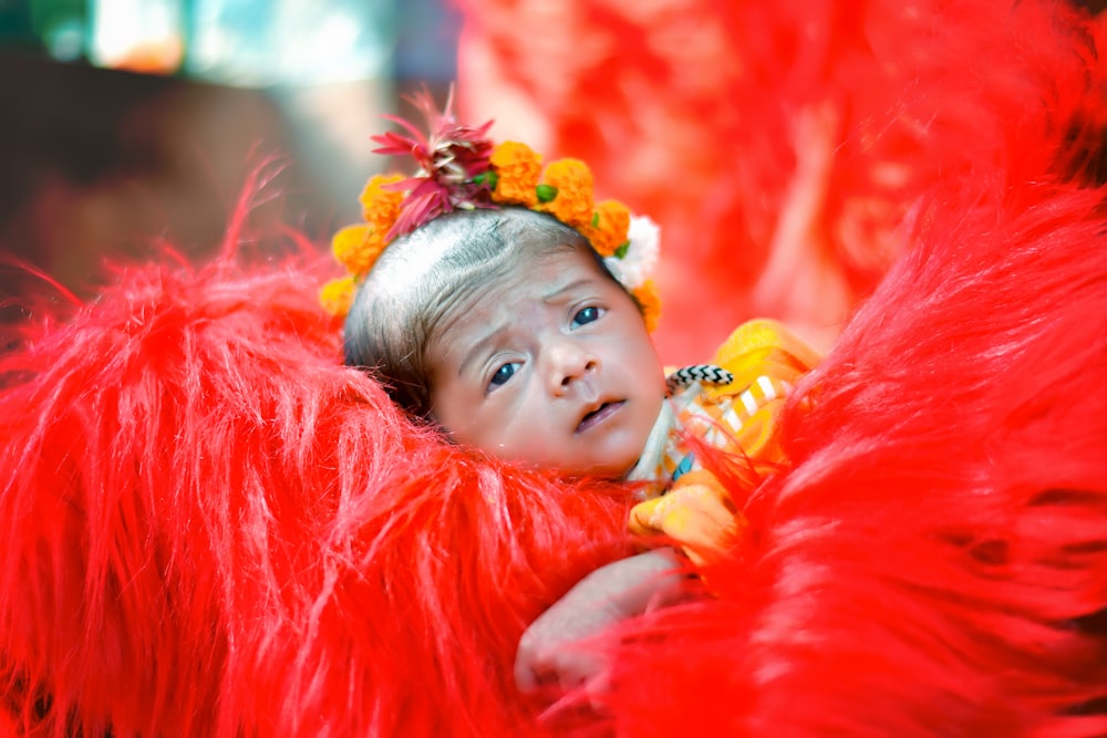 a little girl in a red costume with a flower in her hair