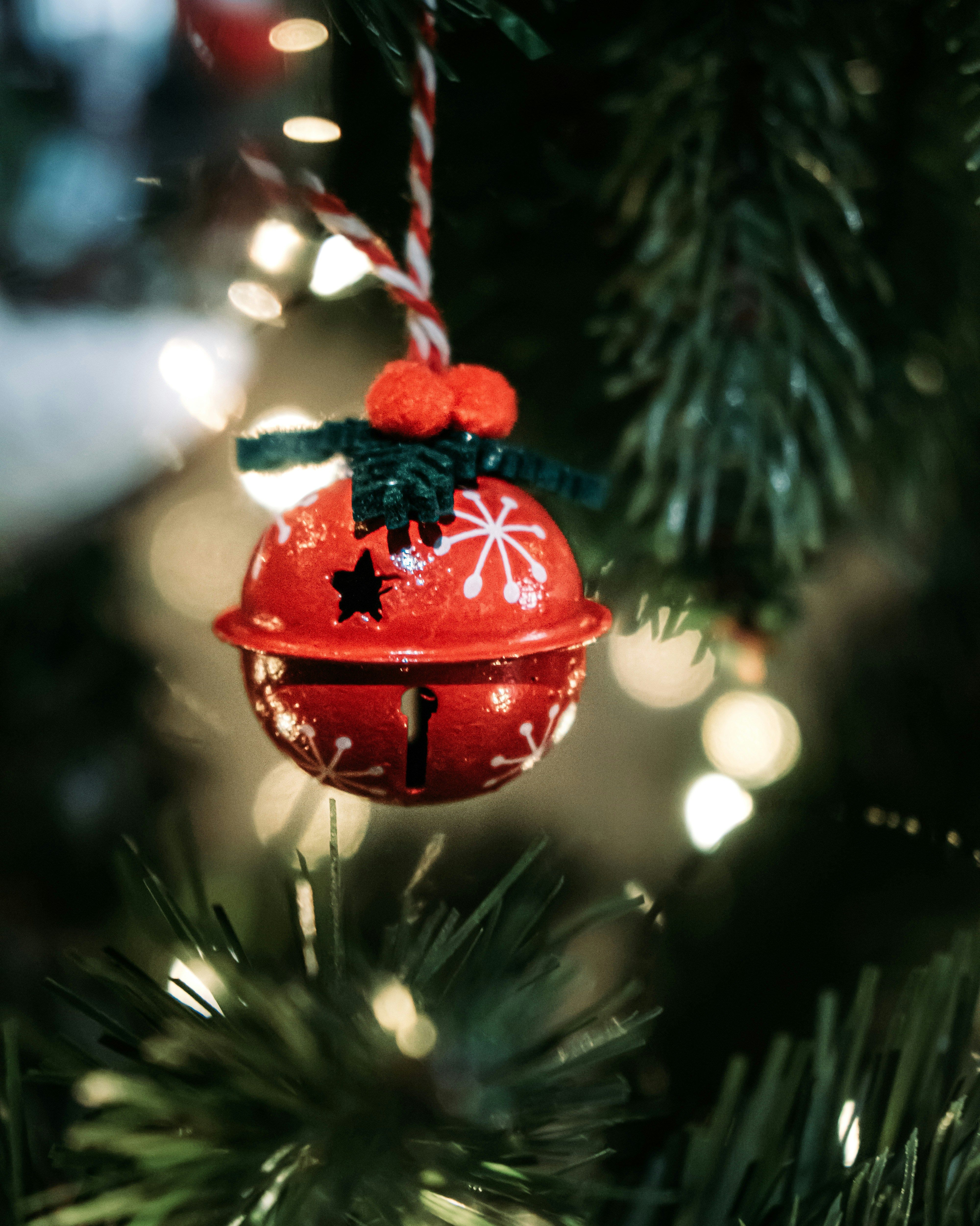 a red bell ornament hanging from a christmas tree
