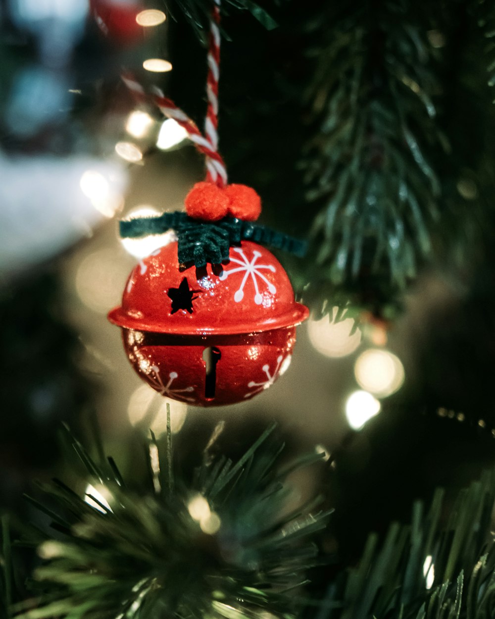 a red bell ornament hanging from a christmas tree