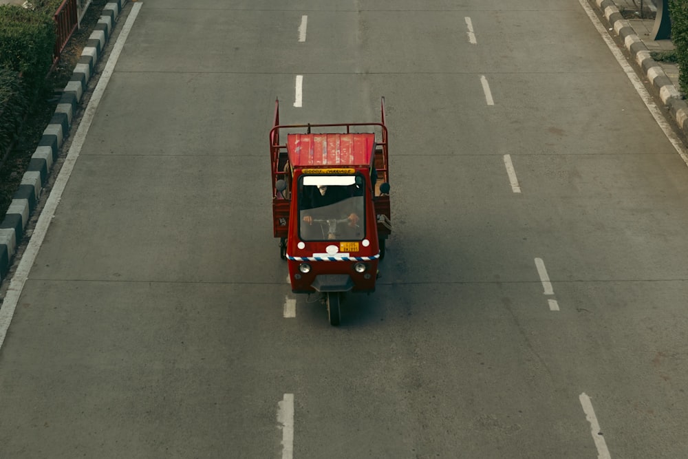 a red truck driving down a street next to a bridge