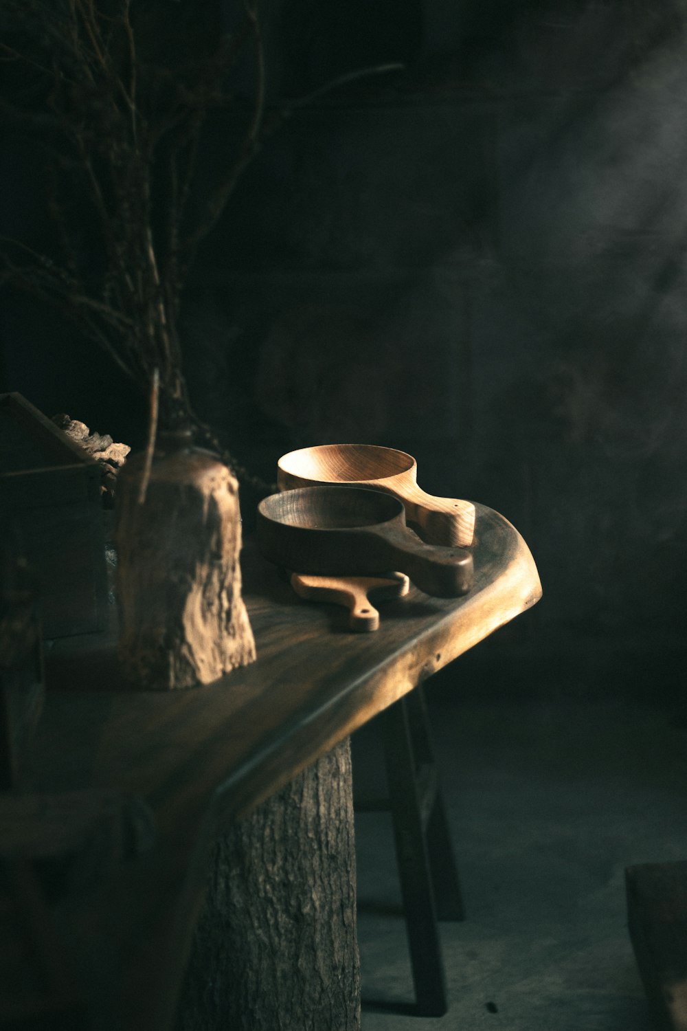 a wooden table topped with a bowl next to a tree