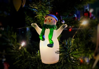 a snowman ornament hanging from a christmas tree
