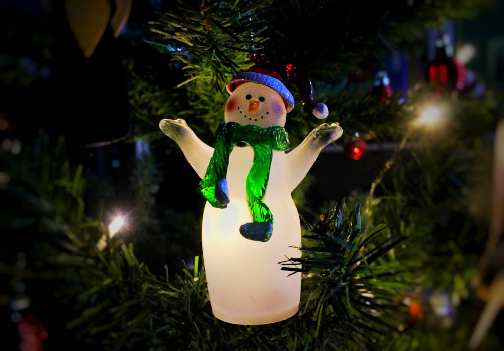 a snowman ornament hanging from a christmas tree