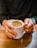 Man holding a steaming cup of coffee with a rustic wooden background.