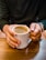 Man holding a steaming cup of coffee with a rustic wooden background.