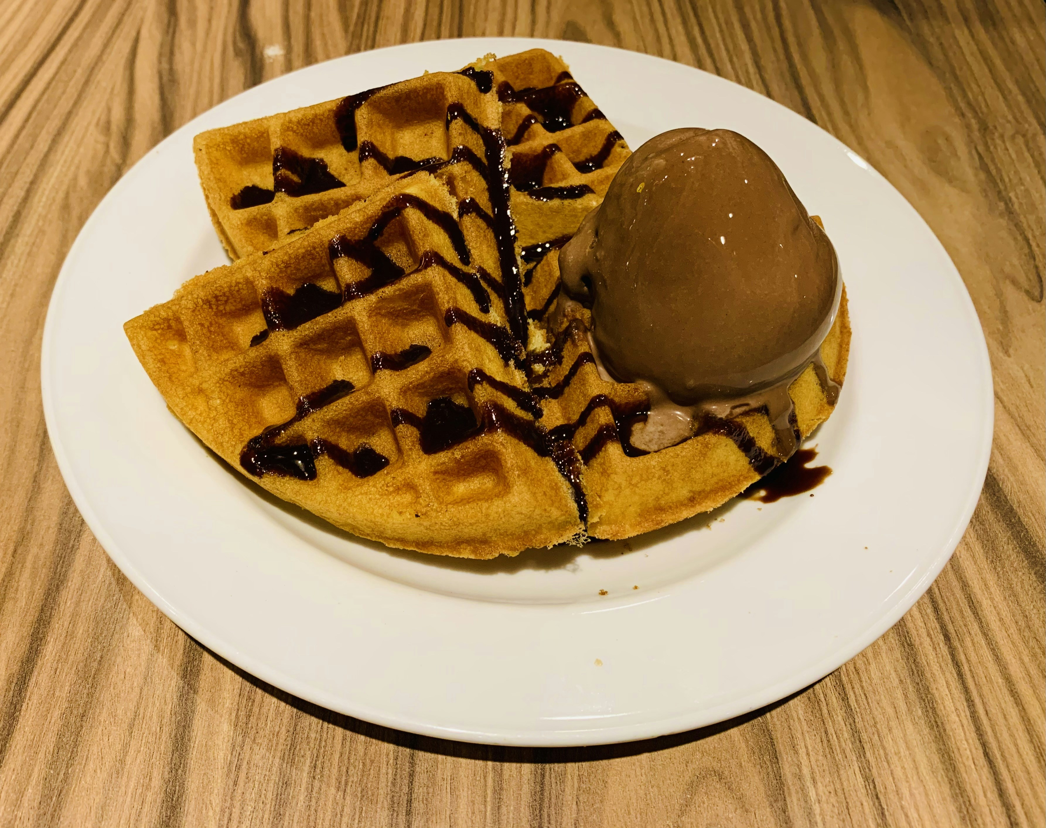 Waffle with chocolate drizzle and a scoop of ice cream