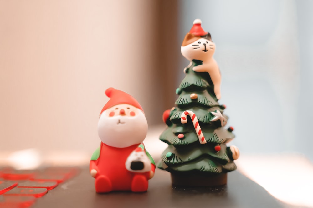 Une figurine de chat à côté d’un petit sapin de Noël