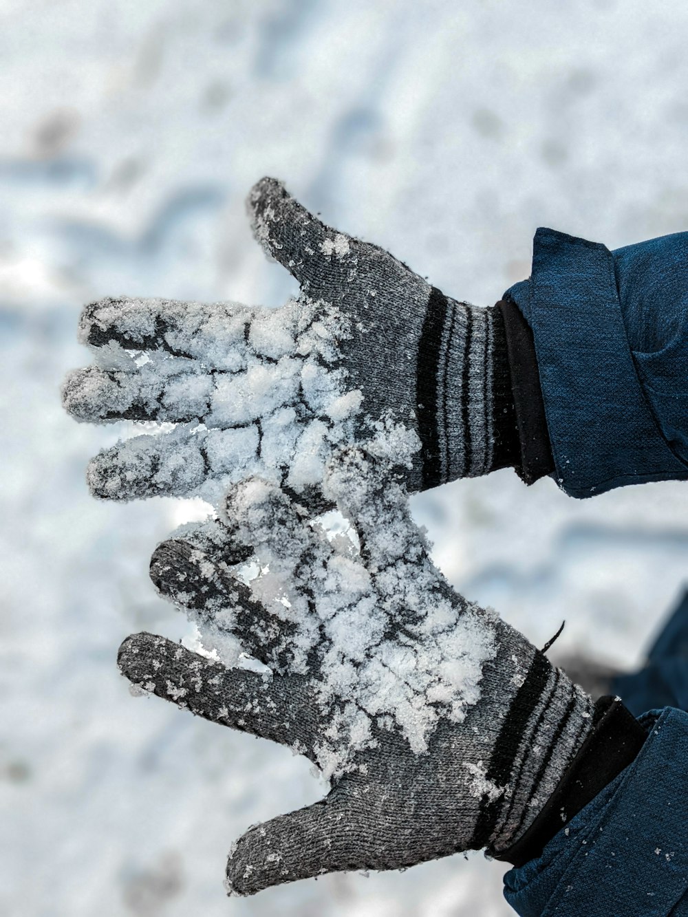 eine Person, die ein Paar mit Schnee bedeckte Handschuhe trägt