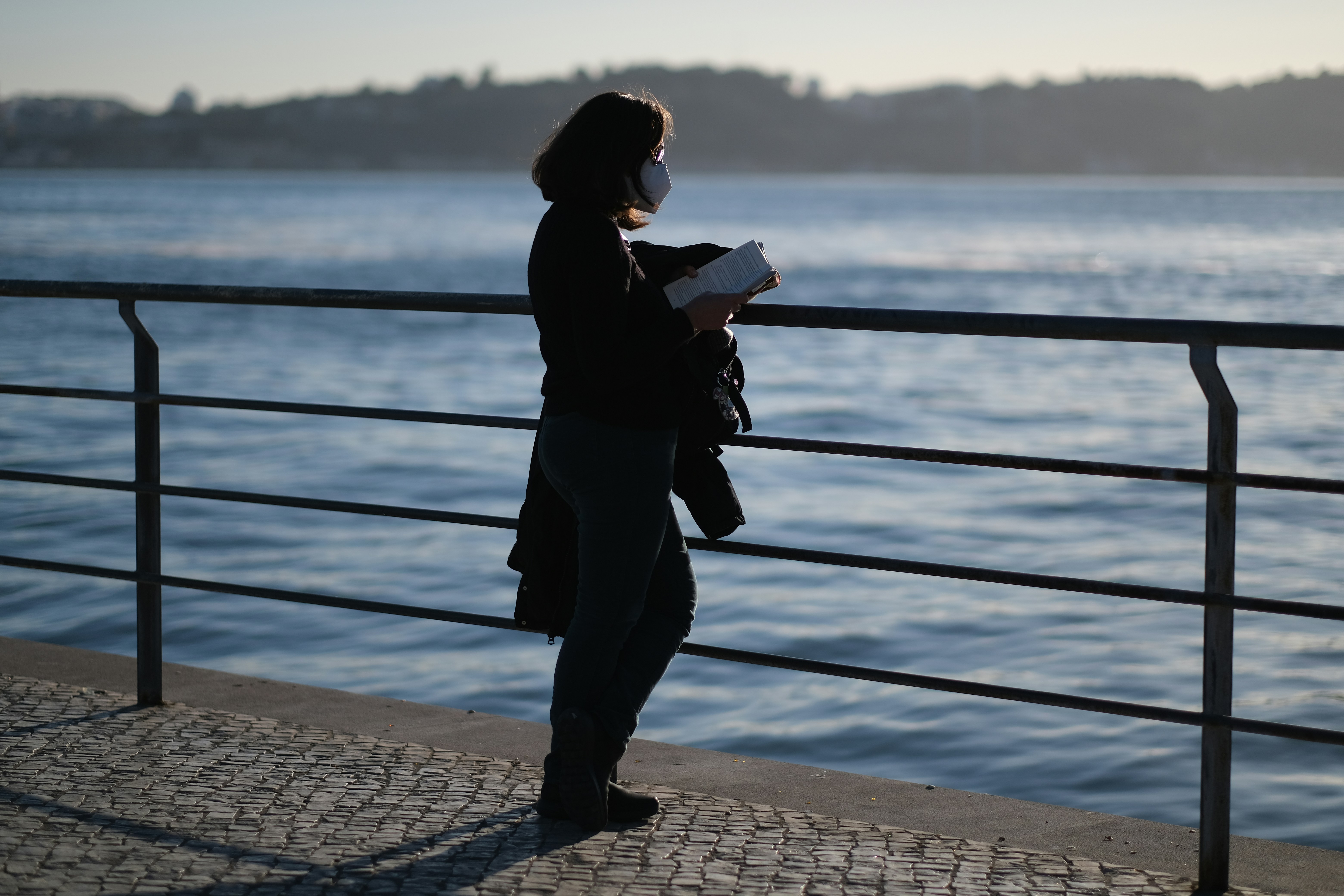 a woman standing on a pier next to a body of water