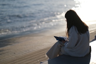 a woman sitting on a bench next to the ocean