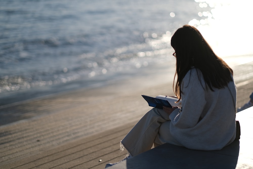 a woman sitting on a bench next to the ocean