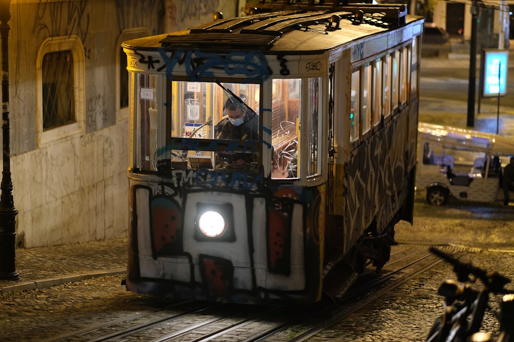 a trolley car with graffiti on it driving down a street