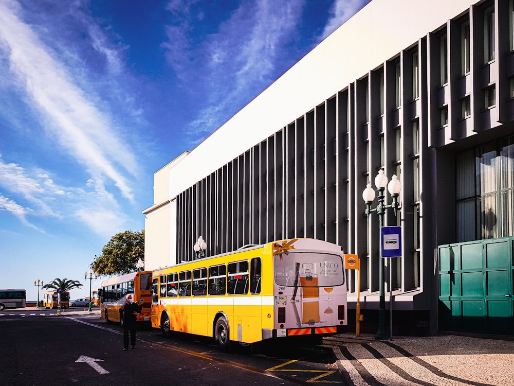 a yellow and white bus parked in front of a building