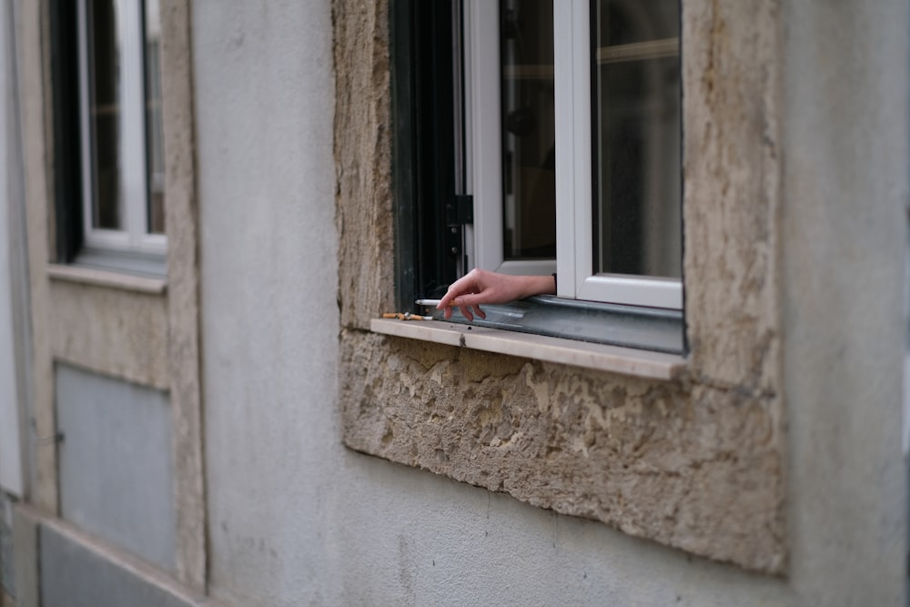 a person's hand reaching out of a window