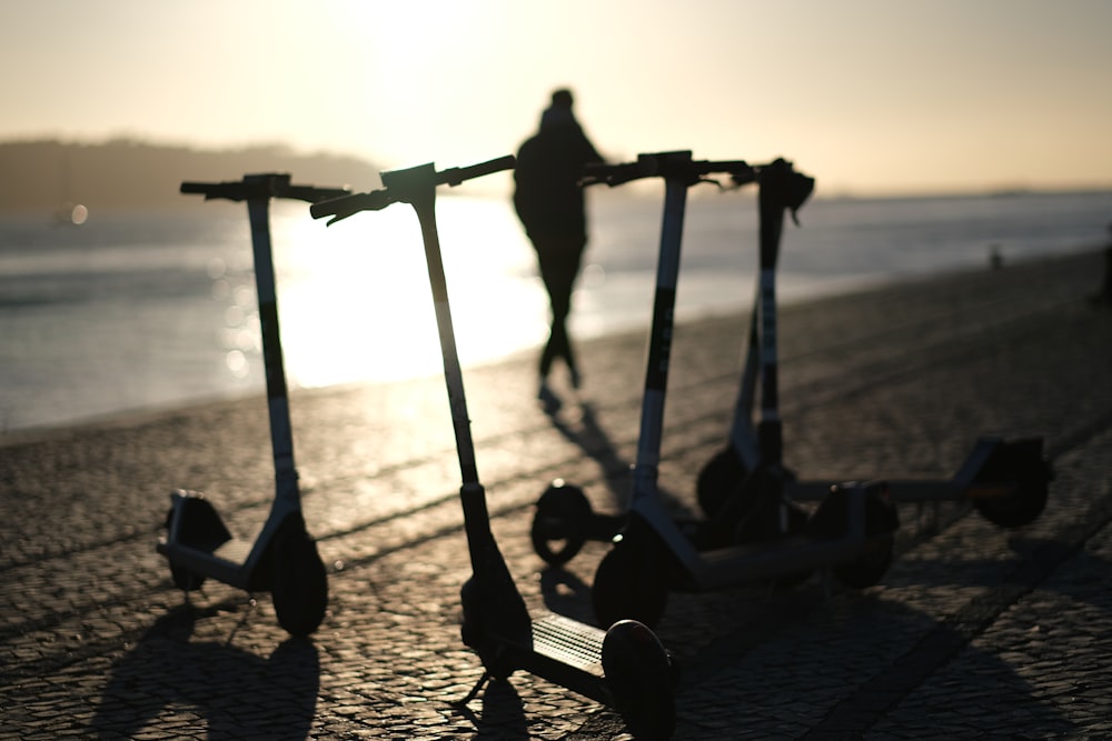 two scooters sitting on the ground near a body of water