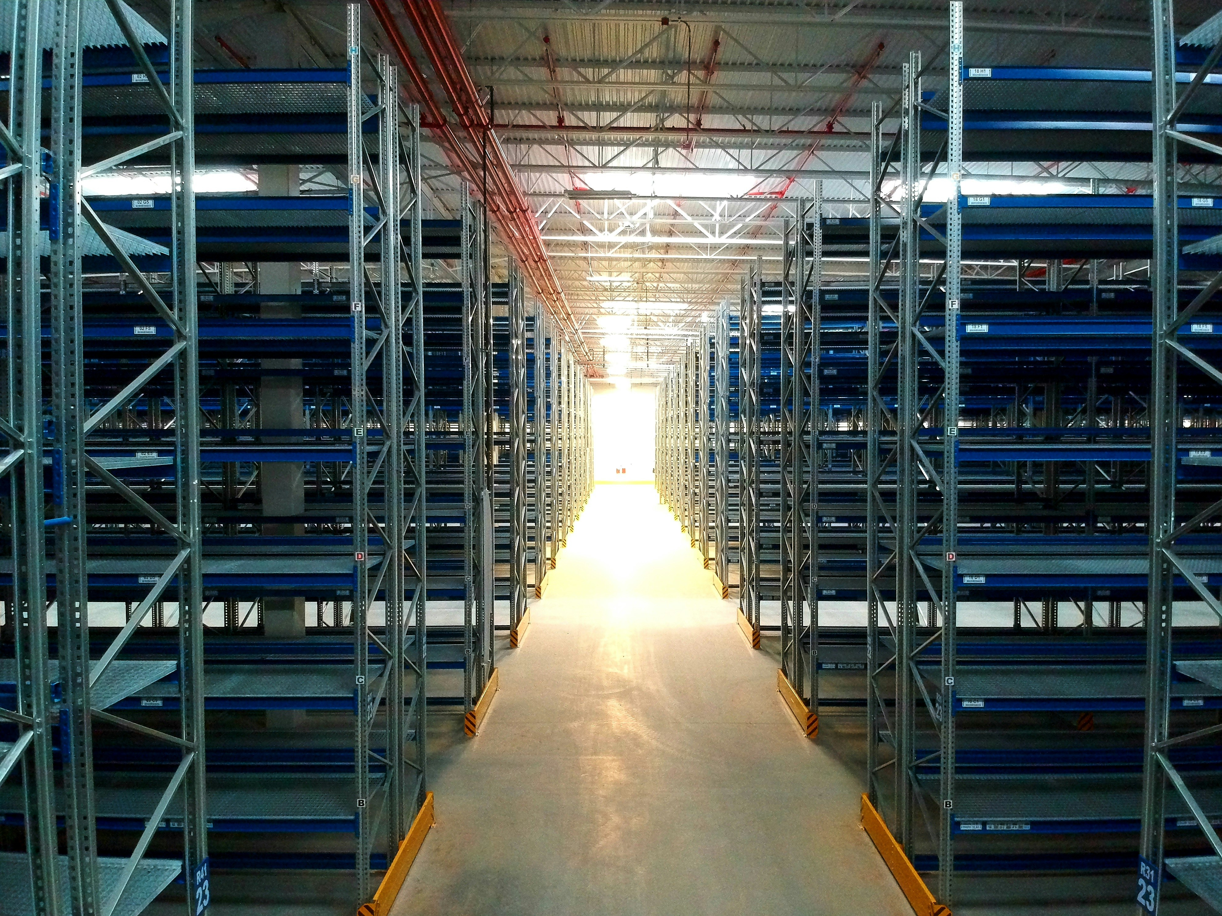 Warehouse logistics center at night with dark blue ambient lighting, storage shelves in deep shadows