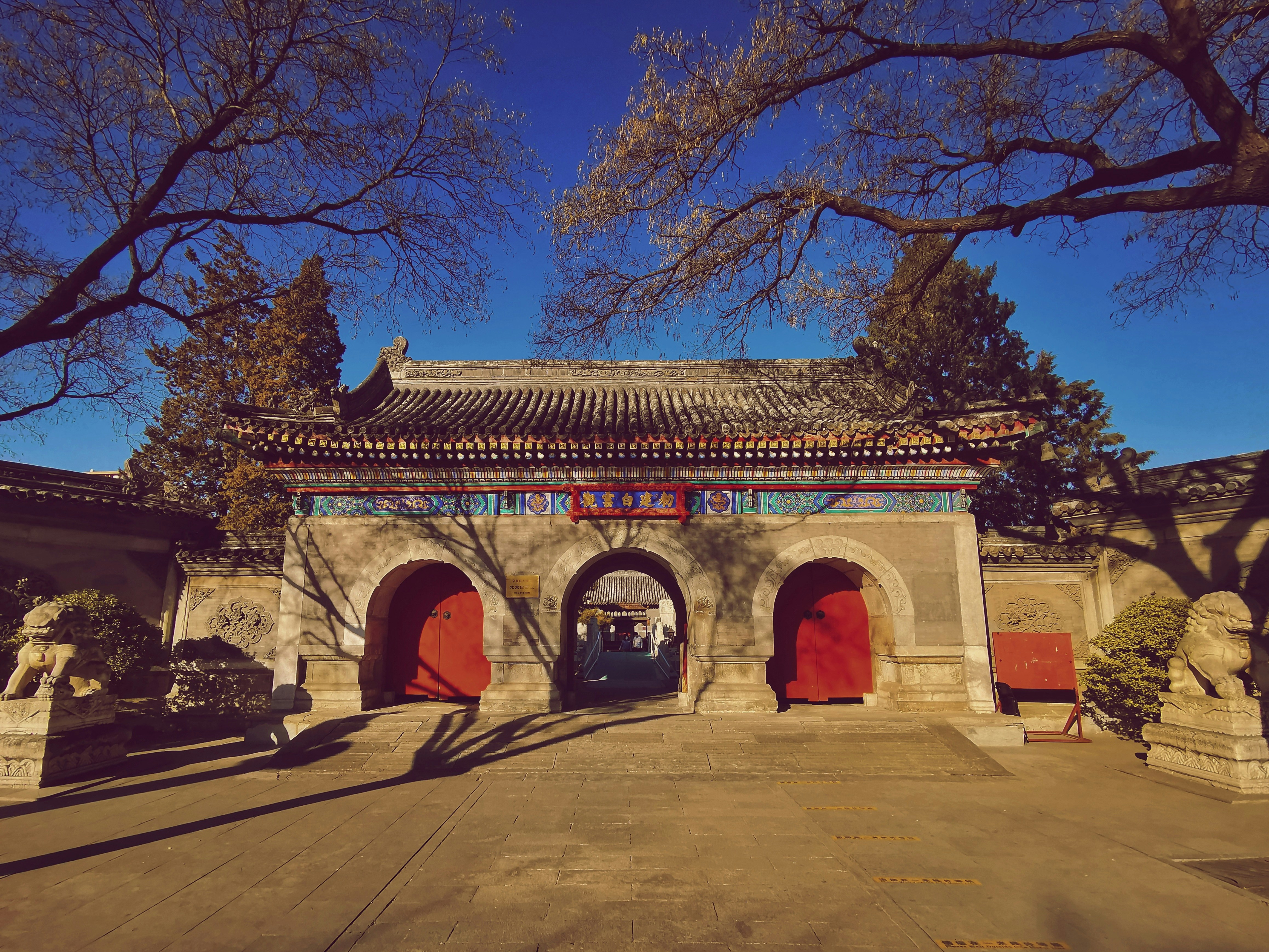 a building with red doors and trees in front of it