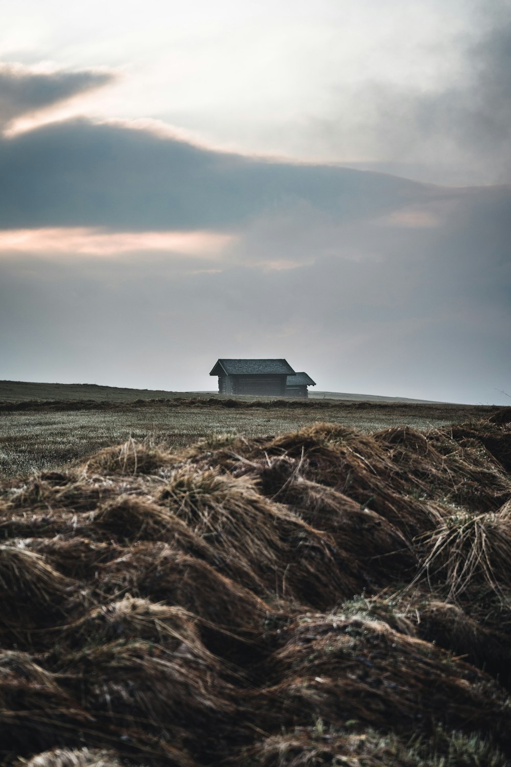 a house on a hill with a pile of hay in front of it