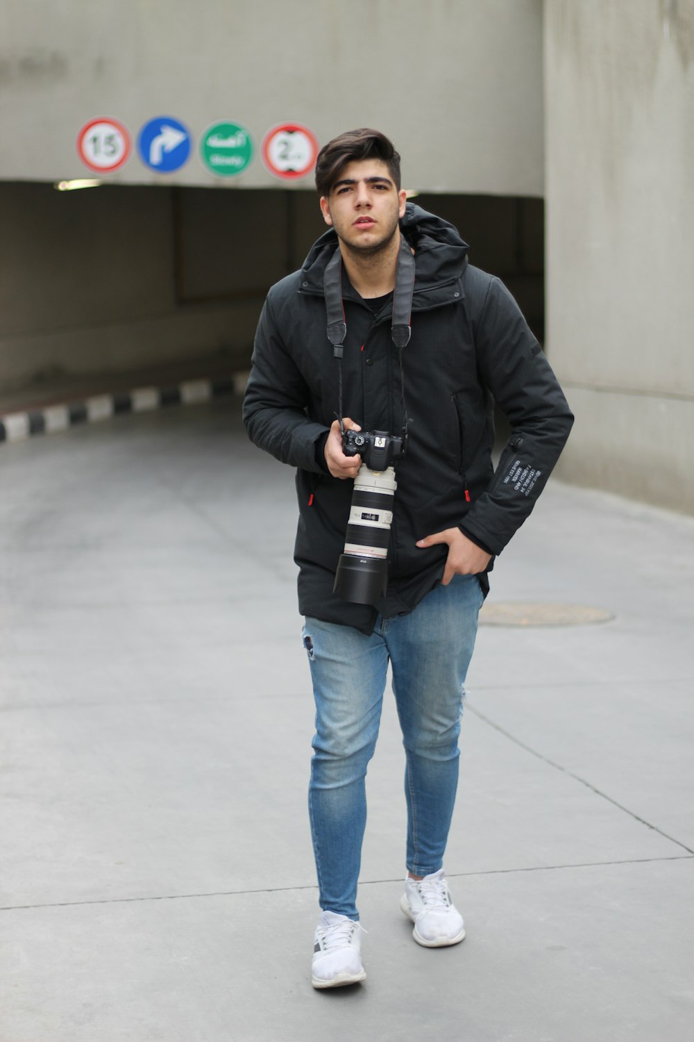 Un uomo con una giacca nera tiene in mano una macchina fotografica