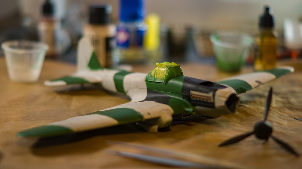 a green and white toy airplane sitting on a table