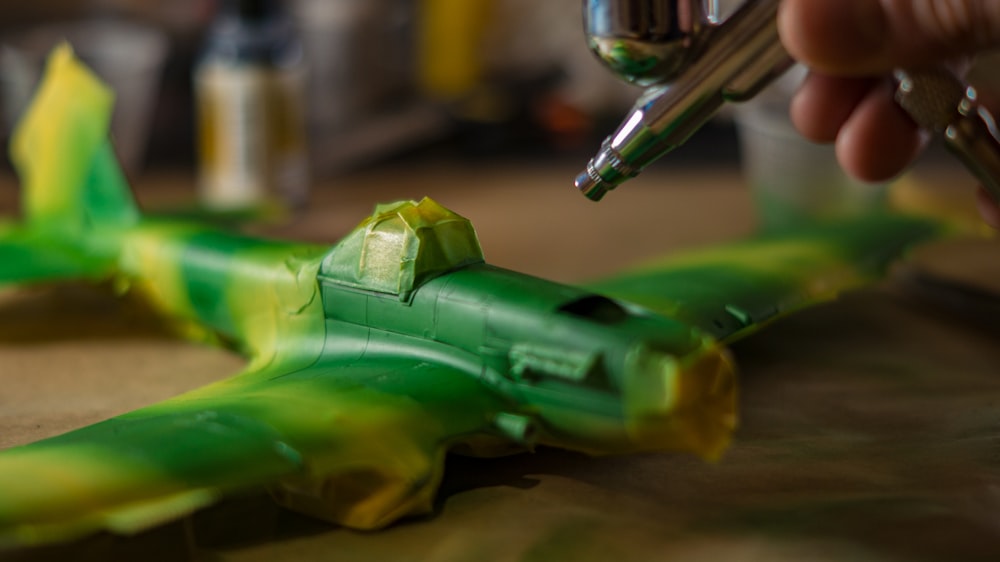 a person is painting a green plastic airplane