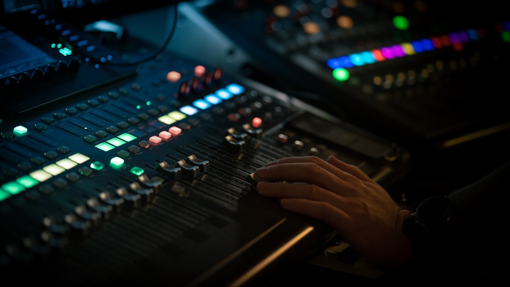 a person's hand on a sound mixing console