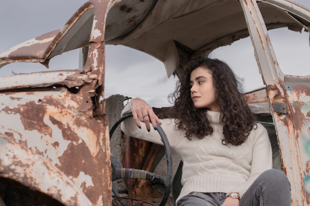a woman sitting inside of an old rusted truck