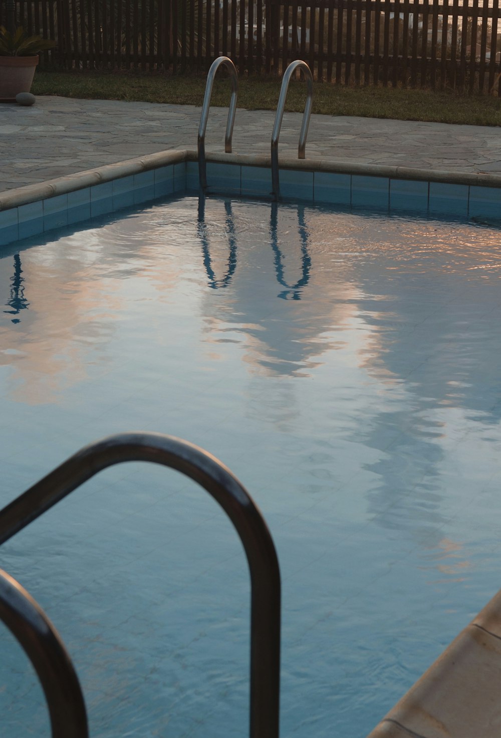 an empty swimming pool with a metal hand rail