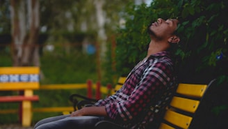 a man sitting on a yellow bench in a park