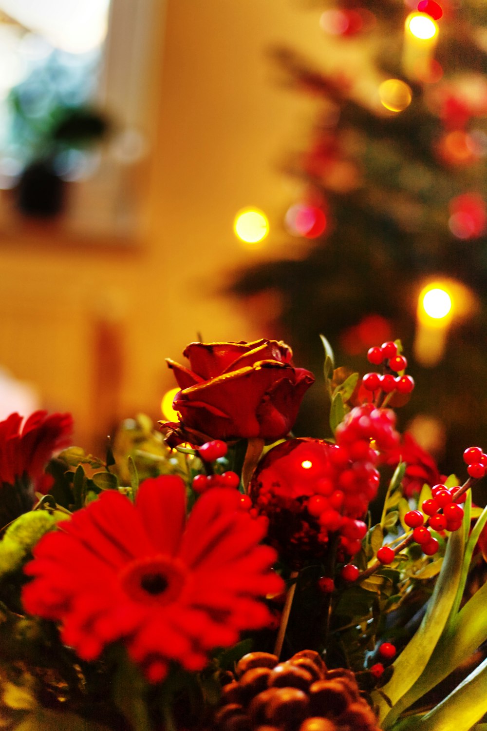 a vase filled with red flowers next to a christmas tree