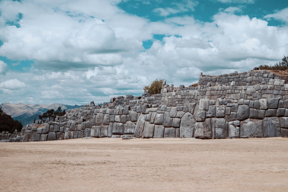 Una gran estructura de piedra sentada en la parte superior de un campo de tierra