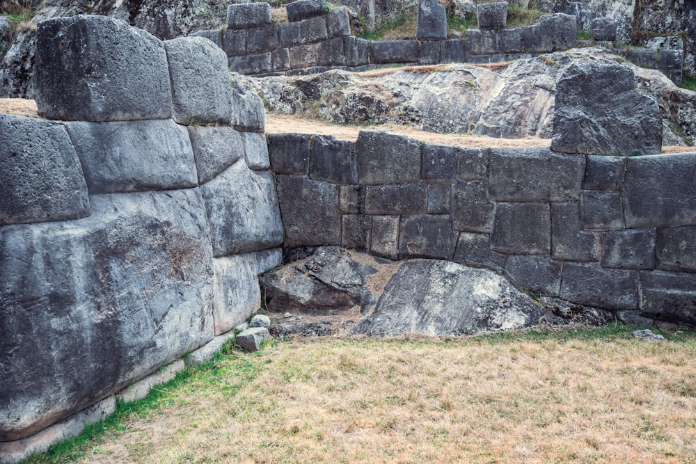 a large stone structure with a grass field in front of it