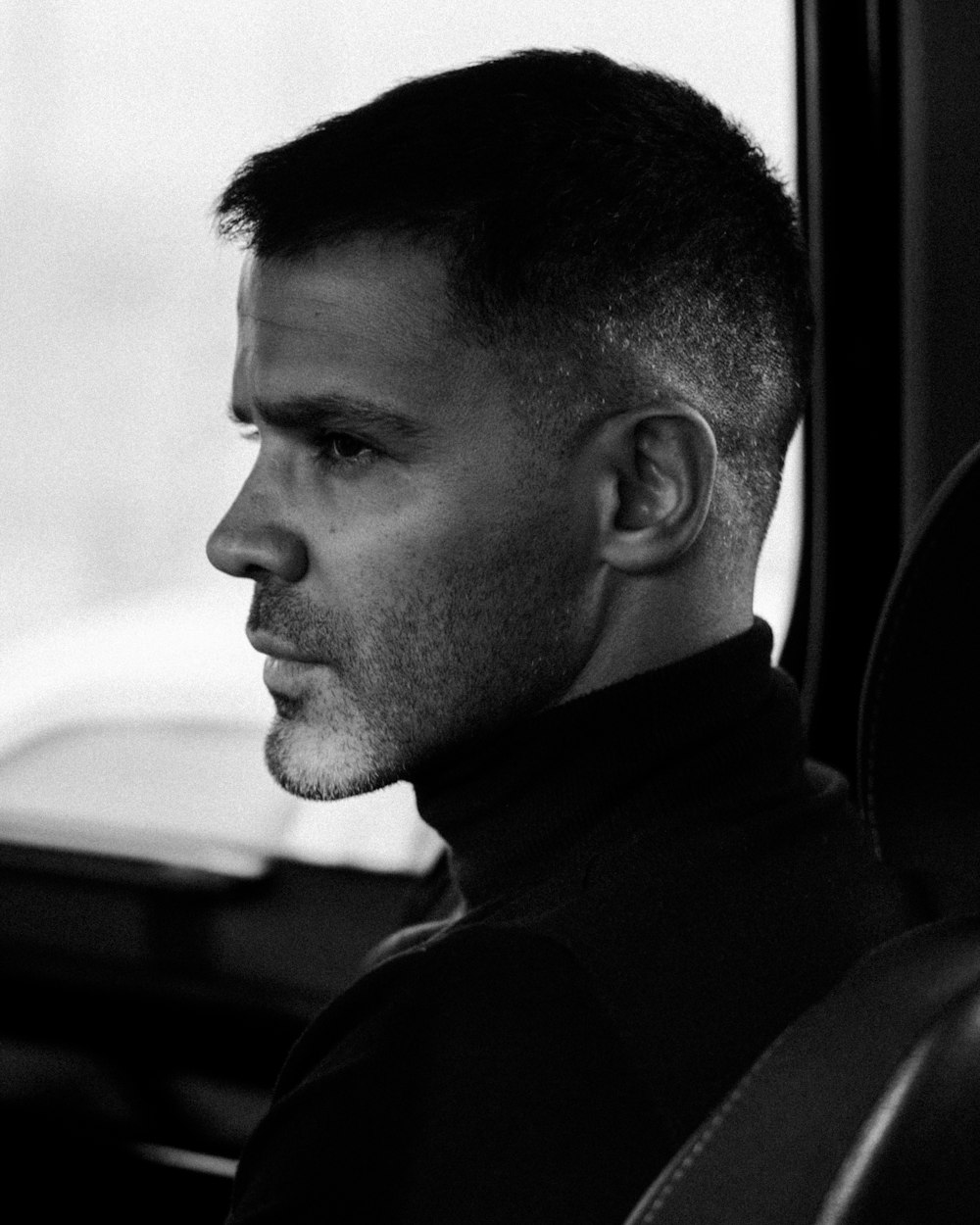 a black and white photo of a man in a car